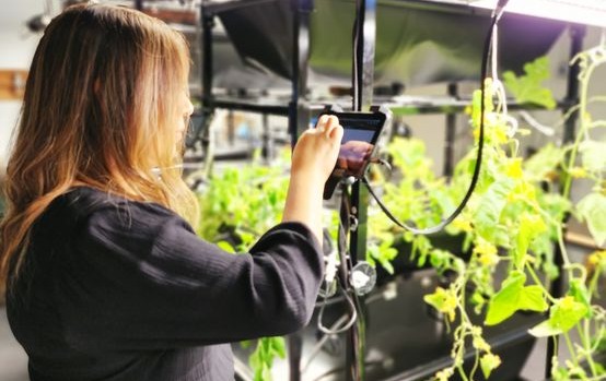 Woman in black shirt uses touch screen on Eden Grow System tower.